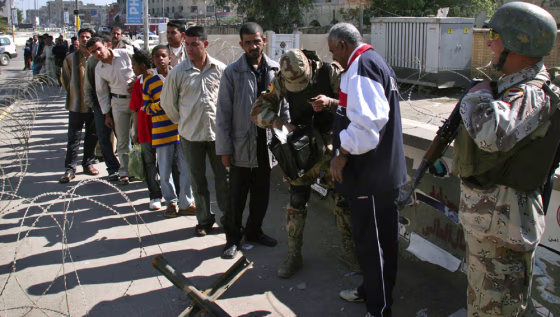 Iraqis wait to get searched at a security checkpoint in Baghdad