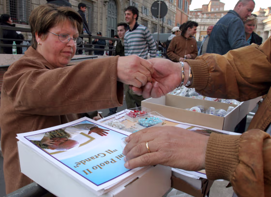 A faithful buys a Pope's souvenir at a stall at the Vatican City, Wednesday. Rome is bracing for an unprecedented flow of pilgrims — some predict their numbers may match the city's own 3 million residents — for the days leading to the pontiff's funeral on Friday.