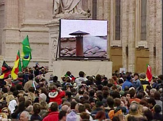 Pilgrims in Vatican City watch the white smoke come out via big screen, signaling the pending announcement of a new pope.