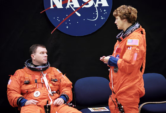 Astronauts James Kelly and Eileen Collins await the start of a training session in the Space Vehicle Mockup Facility at&nbsp;NASA's Johnson Space Center in Houston. Collins and Kelly are wearing training versions of the full-pressure launch and entry suit.