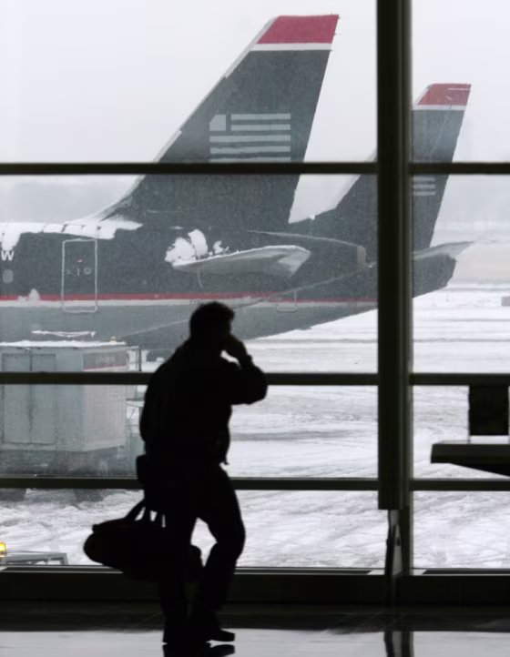 Passenger walks past snow-covered US Airways jets at National Airport in Washington during a winter storm