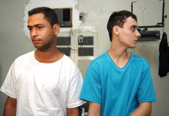 Suspects Ronald Ribeiro Rodrigues, 22, left, and Mayderson Vargas Mendes, 21, seen at a police station, in Guarapari, Brazil, said that they bound, drugged, and killed three people as part of a game.