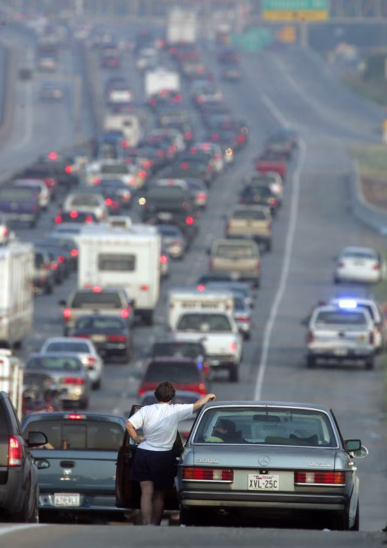 A woman stands outside her car on I-45 near downtown Houston&nbsp;on Thursday. Officials reversed the southbound lane of the interstate to accommodate the thousands evacuating the Texas coast.