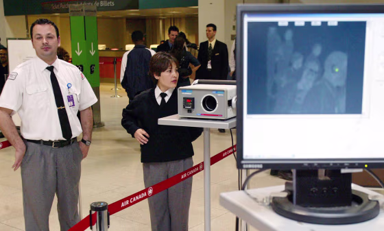 Airport security guards stand next to a thermal imaging camera used to detect fever, a symptom of SARS, as passengers prepare to board their flights at Lester B. Pearson airport in Toronto on May 7, 2003.