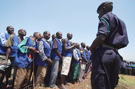 A policeman keeps an eye on former prisoners in Nteko, Rwanda, on Sunday. Some 774 Rwandans convicted by community courts began excavating stones&nbsp;for road construction as punishment for their role in the 1994 genocide of more than half a million people in this small central African nation. 