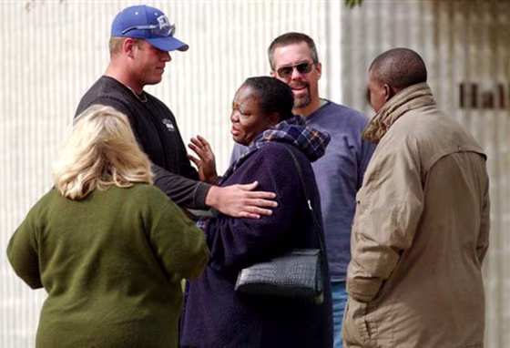 Oluwayinka Adeyooye, mother of missing 21-year-old Illinois State University student Olamide Adeyooye, center, is comforted by family, friends, and law enforcement personnel outside the Normal, Ill., police station in this Oct. 21 file photo. 