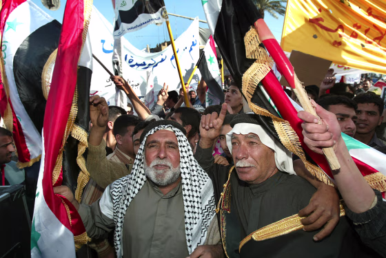 Demonstrators, some waving the national flag, take part in a rally Tuesday in Baghdad, Iraq. More than 10,000 people backing Sunni Arab and secular Shiite politicians marched through Baghdad on Tuesday in support of a national unity government.