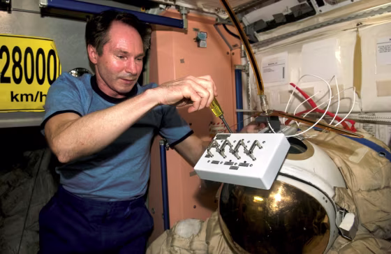 Cosmonaut Valery Tokarev puts finishing touches on an old Russian Orlan spacesuit that will be released by hand from the space station during a spacewalk on Friday.