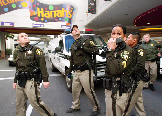 Las Vegas police officers&nbsp;gaze up at a broken window&nbsp;in Harrah's hotel-casino Tuesday&nbsp;after the arrest of&nbsp;a man&nbsp;who allegedly killed another guest&nbsp;and shot at police and paramedics during a six-hour standoff.