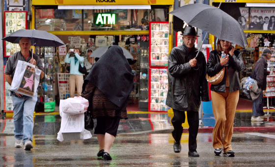 Pedestrians cross a wet Hollywood Blvd. on Monday.