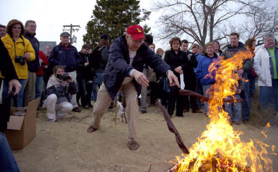 A man tosses his socks into a fire during a ceremony signifying it will soon be warm enough to slide bare feet into boating shoes, Monday in Annapolis, Md.