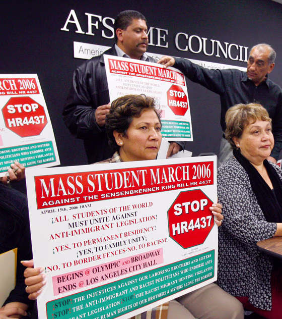 Alicia Flores, bottom left, holds a sign with details for an upcoming immigration demonstration during a news conference Tuesday in Los Angeles.