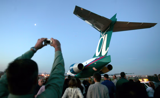 An employee takes a picture as the last Boeing 717 is towed the the flight ramp Thursday in Long Beach, Calif. It was the last commercial passenger jet to the built in California.