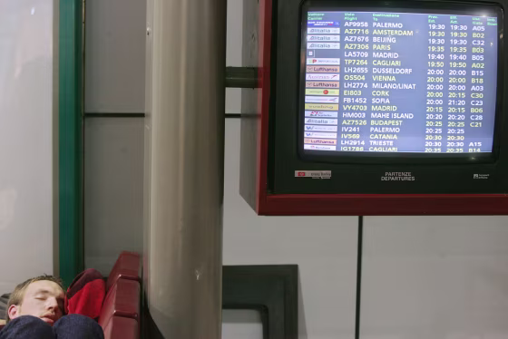 A passenger sleeps near an information b