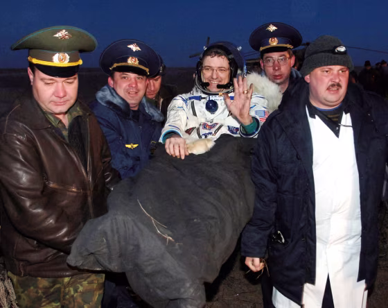 Astronaut Bill McArthur waves to the welcoming crowd gathered on the steppes of Kazakhstan as he is carried from the Soyuz craft that brought him and his crewmates back from the international space station in April. Astronauts returning from the station are carried because they're unaccustomed to gravity's effect.