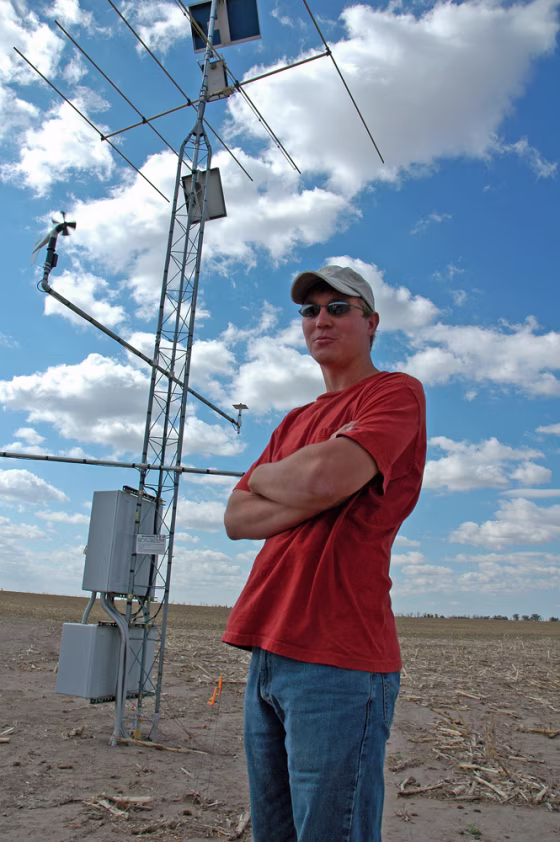 Curtis Johnson, whose family farm outside Imperial, Neb., is enrolled in a test of the potential for ethanol production using corn stalks and similar material, stands in front of a weather station that is part of the scientific study.