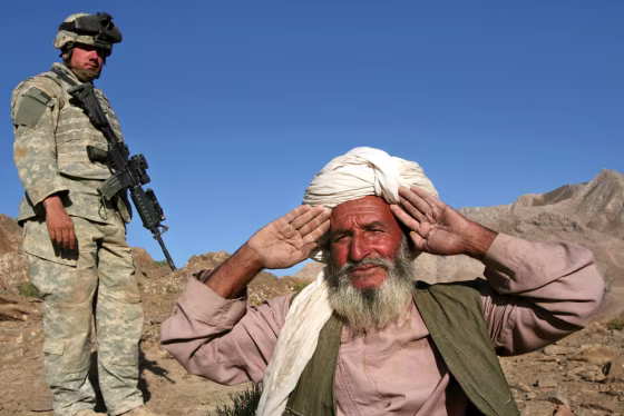 An Afghan villager holds his hands up to show he has no weapons before being searched by U.S. Army Staff Sgt. Mathew Banaszewski at Helmand Province, Afghanistan, on Wednesday.