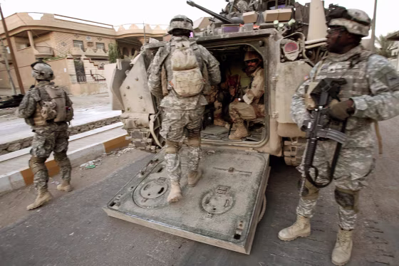 US and Iraqi soldiers load up in back of US Army Bradley fighting vehicle after foot patrol in Hit