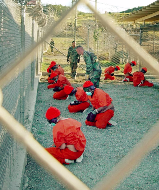 Suspected Taliban and al-Qaida detainees sit in a holding area at Camp X-Ray at Guantanamo Bay, Cuba, during in-processing to the temporary detention facility in this January 2002, photo.