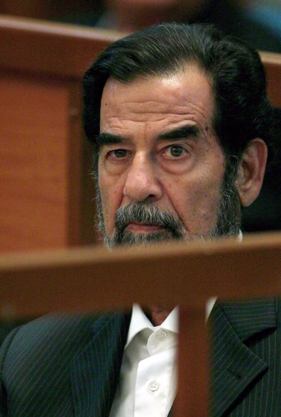 Former Iraqi leader Saddam Hussein looks on during the first day of his trial in Baghdad
