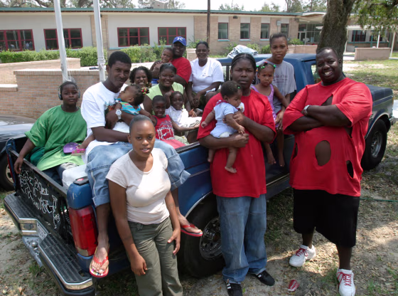 Andre Dunn, right, and members of his extended family pose around the pickup truck that carried them to safety in September 2005 at a Red Cross shelter in Pearl River, La. John Russell, who was slain in New Orleans in late July, is seated on the truck,&nbsp;second from left, with his daughter in his arms.