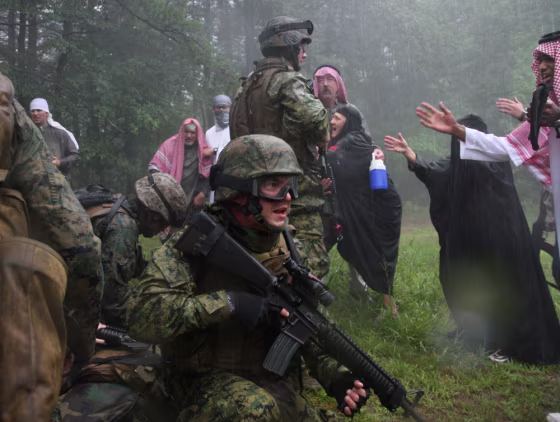 Sgt. Kristopher Schlueter, middle, participates in an urban combat drill with role players dressed as Iraqis, as Marines from the 4th Civil Affairs Group out of Anacostia prepare in Quantico, VA, to deploy to Fallujah, where the insurgency continues and anger among the civilian population remains high. 