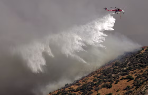 A helicopter drops water on the Pinnacles Fire near Lake Arrowhead