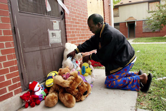 Shawn Crawford places stuffed animals in front of an apartment in the John DeShields public housing complex Sunday in East St. Louis, Ill., near where three children were found murdered Saturday. 