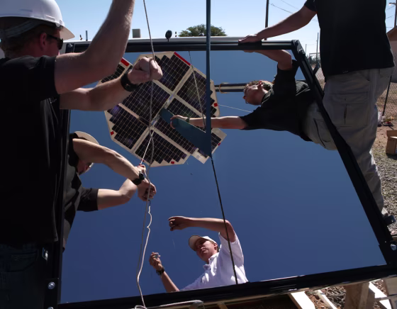 University of Saskatchewan Space Design Team members adjust their beam-powered climber, seen here reflected in a mirror, before&nbsp;a final attempt&nbsp;to have the device ascend&nbsp;a tether on Sunday. The climber stopped several feet up, apparently because the reflected beams of light went off target at the wrong time.