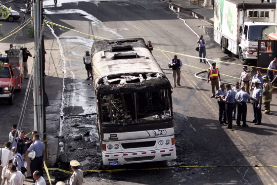 Police, firefighters and rescue workers stand Monday by a burned bus in Panama City, Panama. An official said the bus was operating with faulty brakes and no license plates.