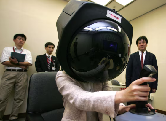 Toshiba Corp. employee Aira Hotta demonstrates prototype headgear that enables her to get a 360-degree view on a dome-shaped screen. Toshiba, which plans to market the gadget within 2 to 3 years, aiming at attracting people such as virtual reality gamers.