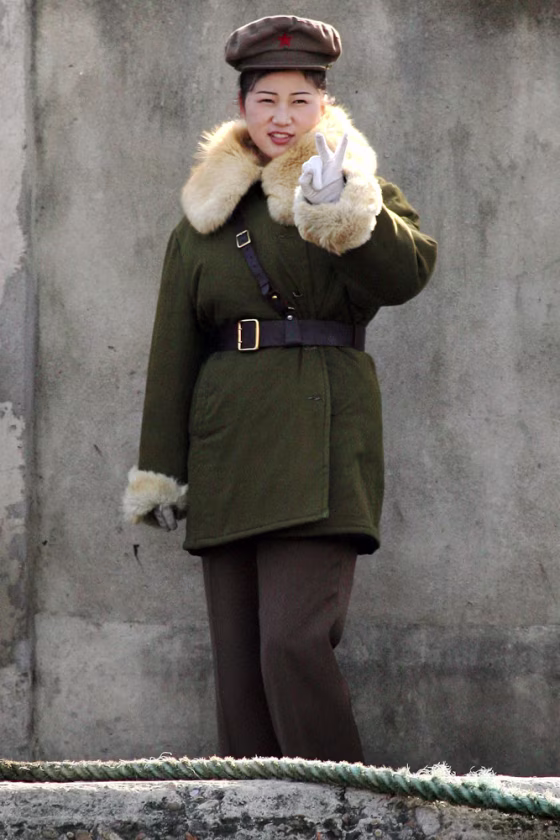 North Korean soldier gestures as she is being photographed, on the bank of the Yalu River near the North Korean town of Sinuiju, opposite the Chinese border town of Dandong