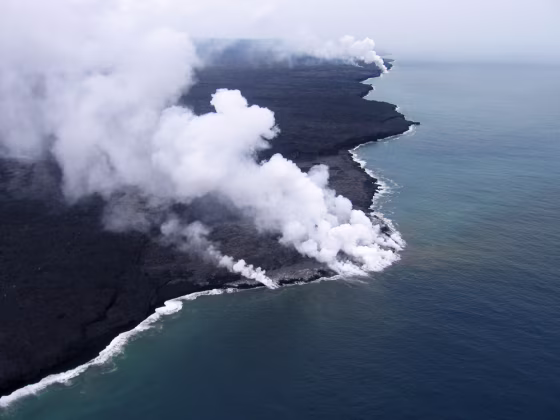 Steam is seen rising from several sites as lava enters the ocean at East Laeapuki, Hawaii. Visitors to one of the world's most active volcanoes are being kept hundreds of feet away from a 55-acre lava delta that authorities believe may soon collapse into the Pacific Ocean. 