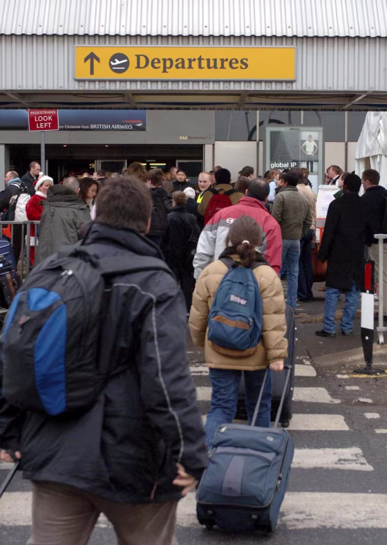 Passengers carry their luggage towards the departures area at London's Heathrow Airport. British Airways will soon charge passengers for carrying two bags.