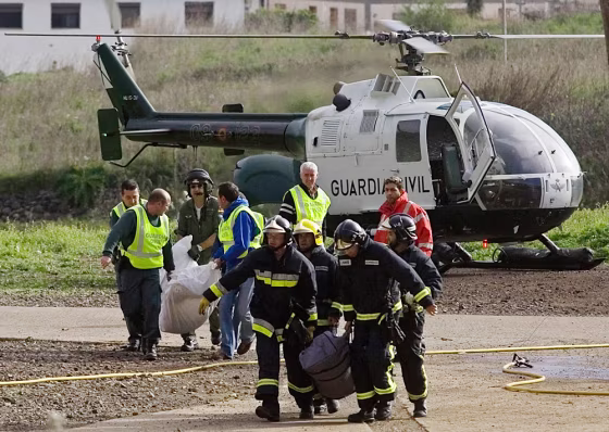 Civil Guard officers and firefighters carry plastic bags with the remains of the two persons found dead in the underground tunnel complex.