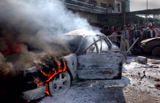 Iraqis gather at a car that caught fire after two bomb blasts in Kirkuk, 180 miles north of Baghdad, Iraq, on Saturday.