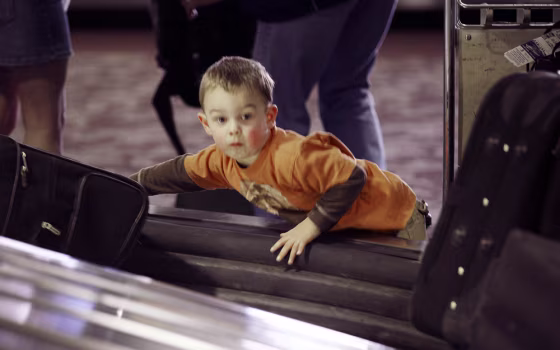 Child looks for luggage in terminal at airport in Phoenix, Arizona