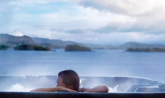 A Solstrand Hotel & Bed guest enjoys an outdoor Jacuzzi overlooking the fjords.
