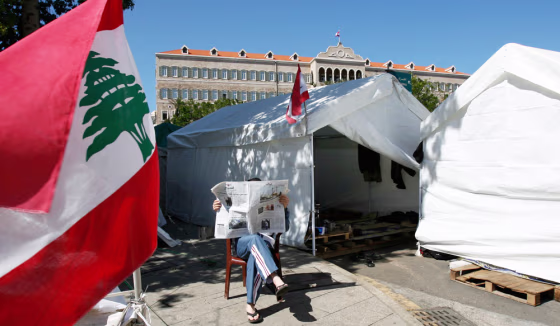 A Lebanese Hezbollah member reads a newspaper near a tent where the opposition has been camped out near the government's headquarters in central Beirut