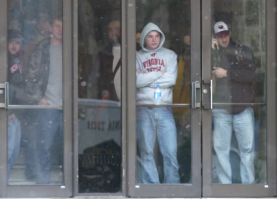 Virginia Tech students watch from a campus doorway as police move into&nbsp;the area where&nbsp;a shooting took place Monday.