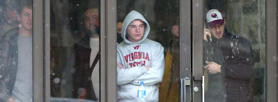 Students watch from the doorway of Virginia Tech's McBryde Hall and get updates via cell phone during Monday's shootings. The tragedy is raising awareness about how to keep students safe — and how to&nbsp;broadcast alerts.