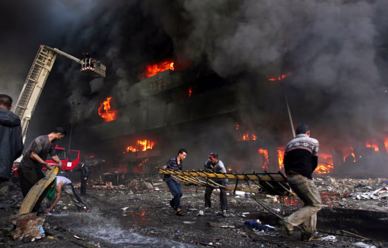 Firemen and residents rush to a burning building after twin bomb attacks at Shorja market in Baghdad