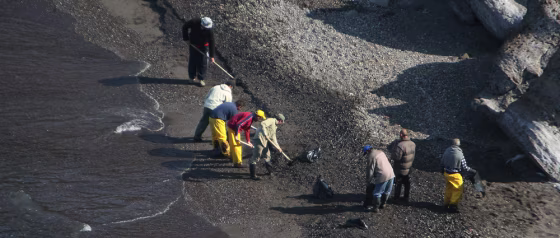 Clean-up crews use shovels to remove oil from a pebble beach on Santorini, Greece, in this file photo.