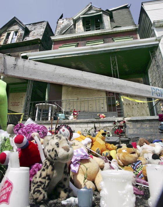 A pile of stuffed animals stands in front of two row houses Wednesday, June 13, a day after a fire killed five young children in Pittsburgh. 