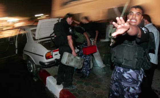 Members of Hamas security force inspect a car targeted by an Israeli air strike in Gaza