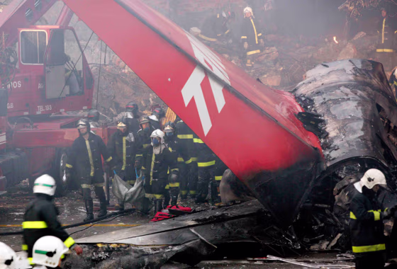 Firemen carry the body of a victim of the crash of a TAM airlines Airbus A320 that slid off the runway of Congonhas airport