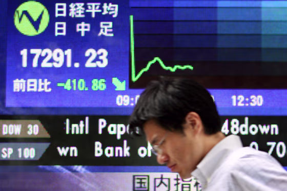 A man walks past a share prices board in