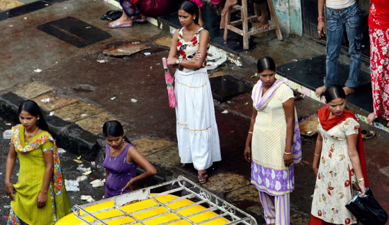 Sex workers stand on a roadside pavement in a red light area in Mumbai