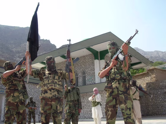 Pro-Taliban militants stand before an occupied&nbsp;shrine in Pakistan's tribal area of Mohmand&nbsp;on Monday.&nbsp;Officials sought the help of tribal elders Tuesday to convince&nbsp;the militants to end their occupation.