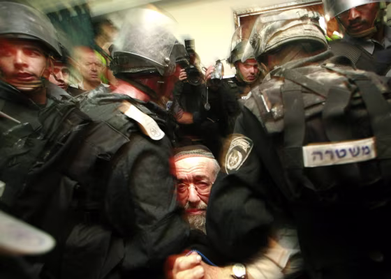 Israeli security forces restrain a settler in the West Bank city of Hebron